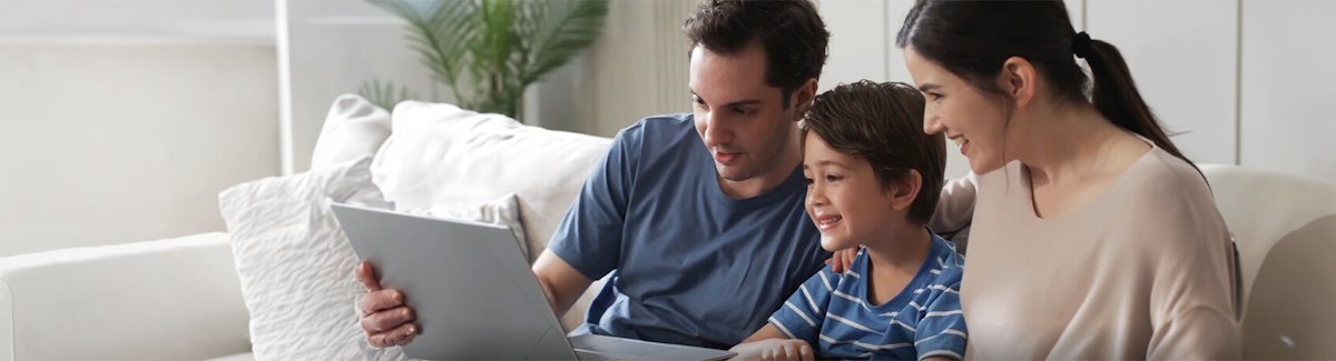Eine Familie genießt es, in einem Wohnzimmer auf dem Laptop zu sitzen.