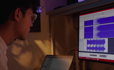 Eine Person, die die Audio-Wellenformen auf einem Computerbildschirm überwacht, um sicherzustellen, dass jeder Treiber gemessen, sortiert und für einen einheitlichen Frequenzgang zwischen den Hörmuscheln gepaart wird.